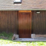 Porte de service en bois exotique. Ouverture sur l'extérieure avec barre anti-panique.